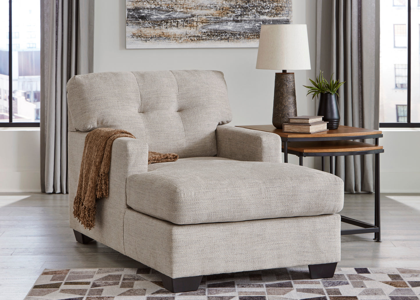 Beige armchair in a living room setting with a side table and lamp.