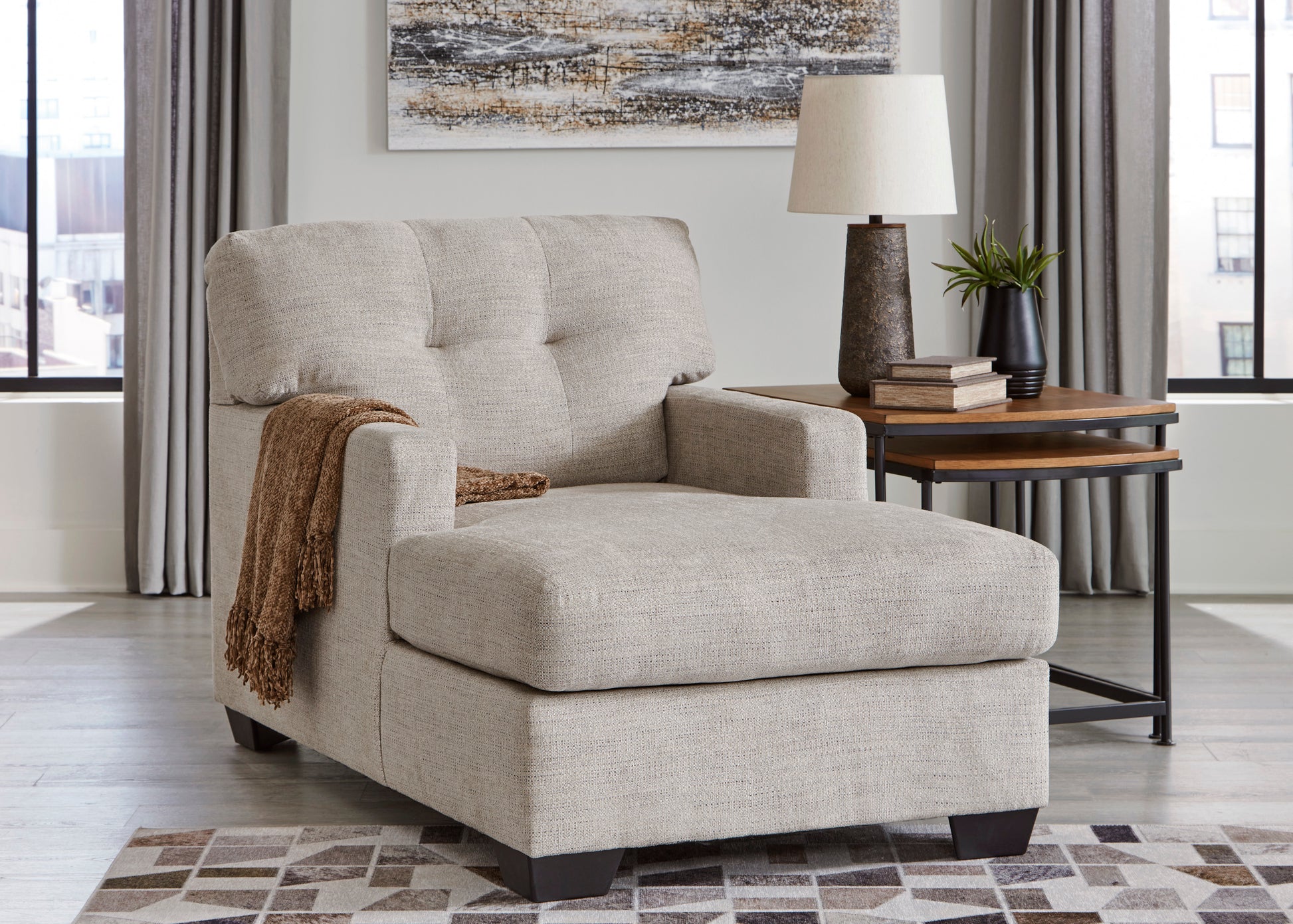 Beige armchair in a living room setting with a side table and lamp.