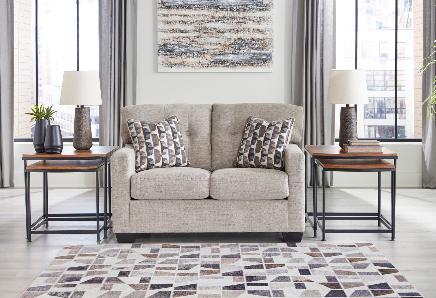 Beige sofa with patterned cushions in a living room setting with side tables and a rug.