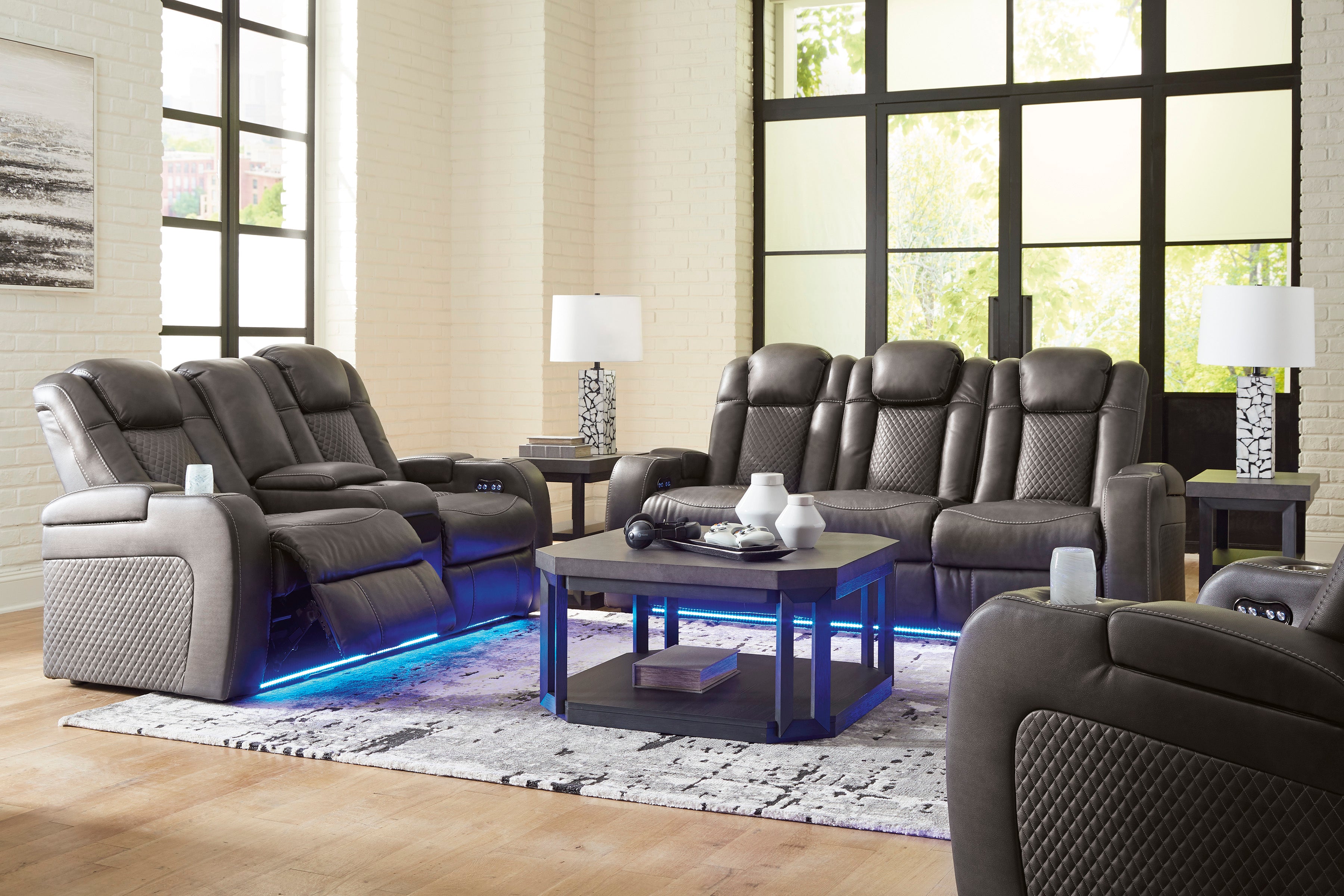 Gray reclining sofa set in a living room with large windows.