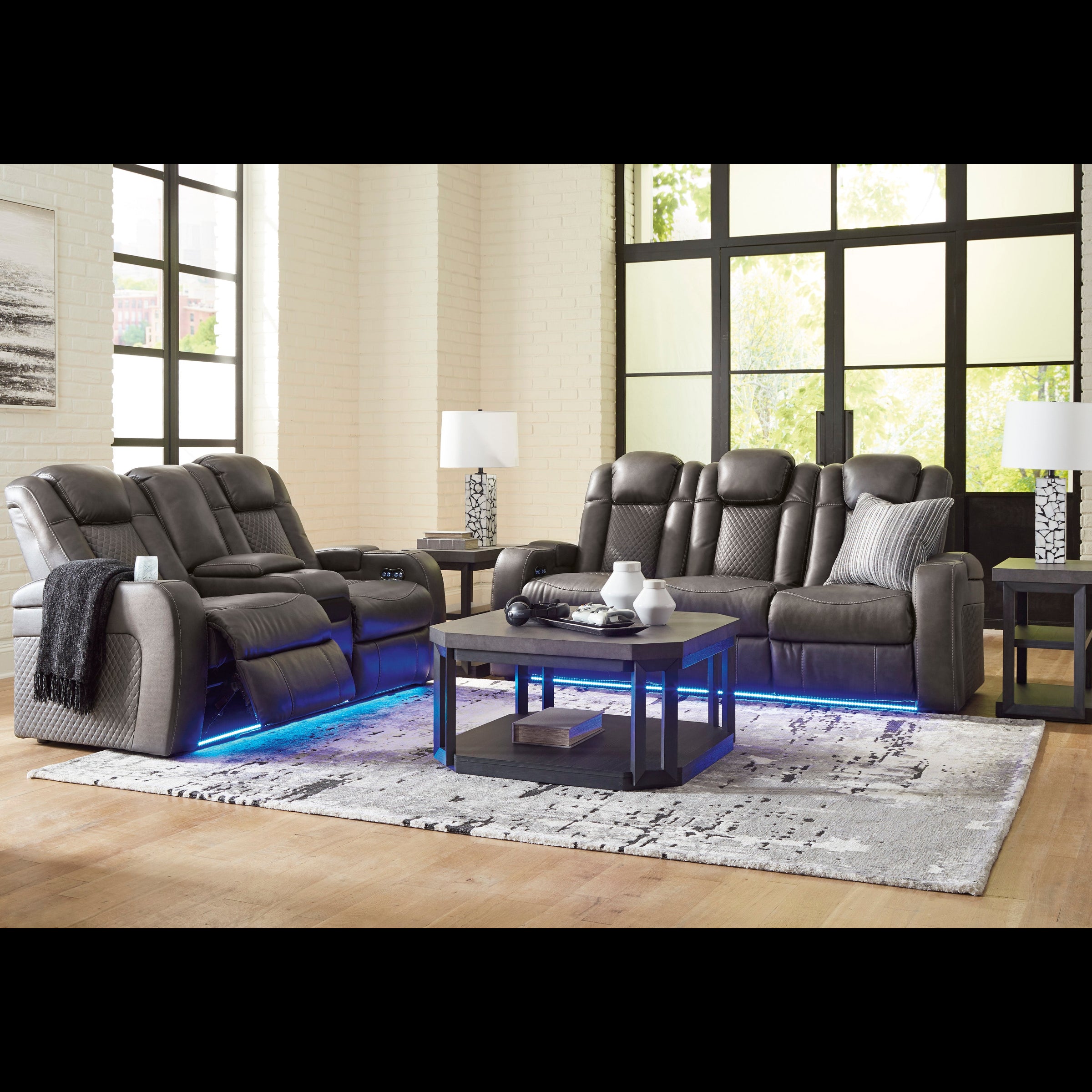 Gray reclining sofa set in a living room with a coffee table and lamps.