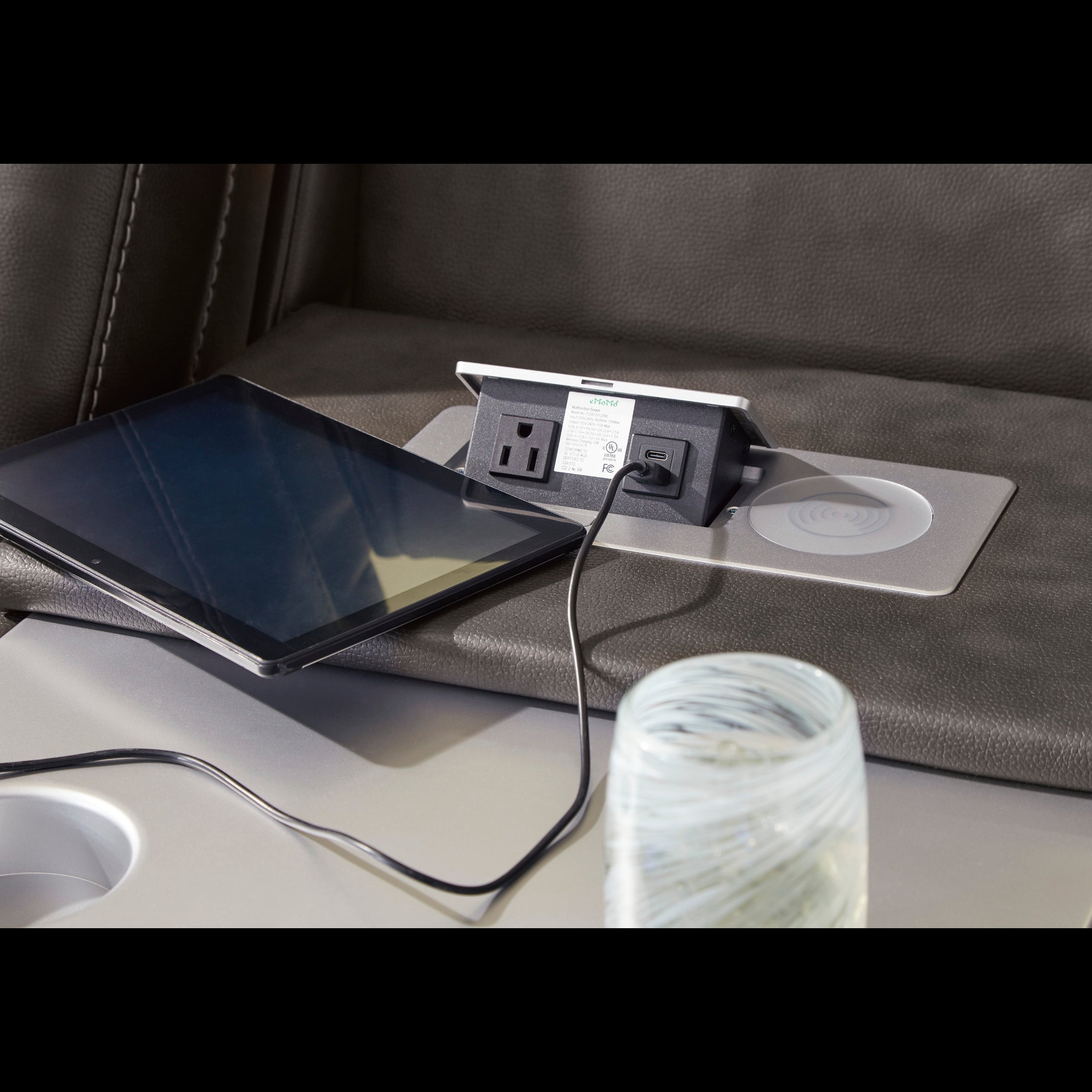 Tablet charging on a car's built-in charging station with a cup holder and water bottle.