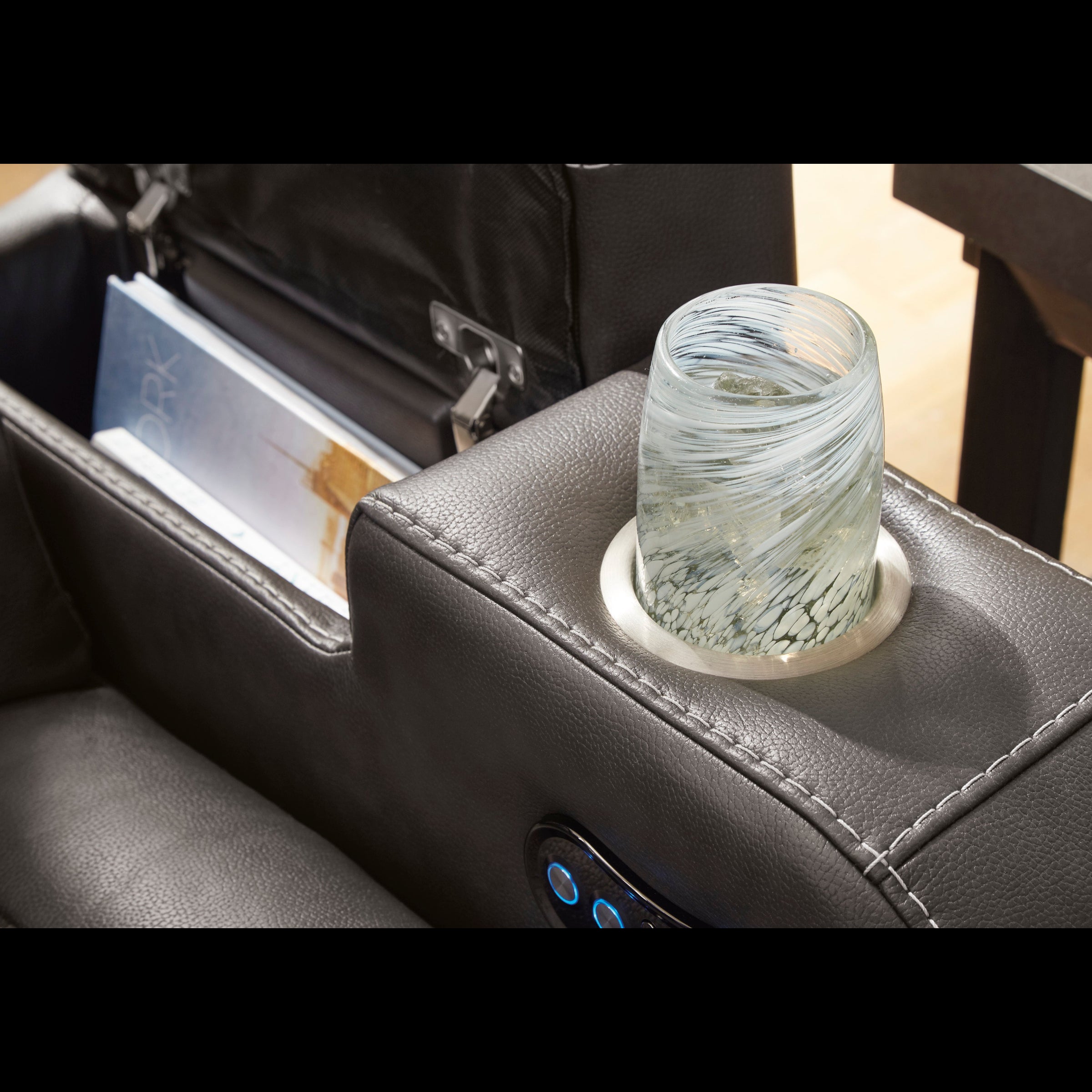 Glass of water on a car armrest with a magazine inside the cup holder.