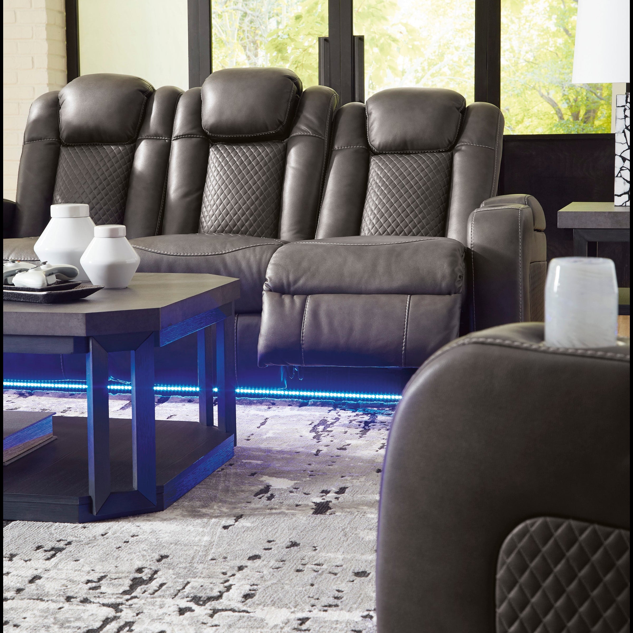 Gray leather recliner chairs in a living room setting with large windows.