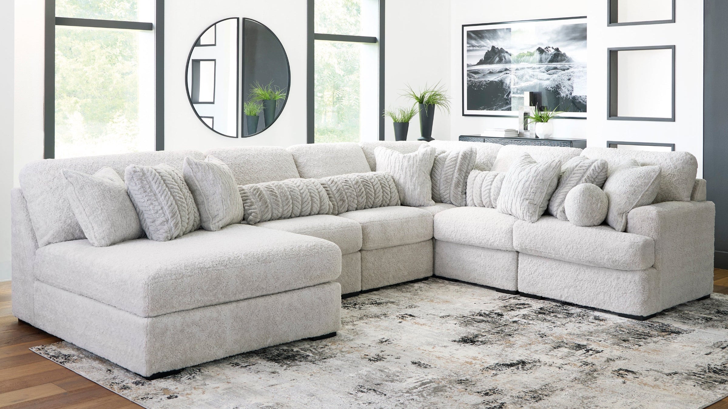 Gray sectional sofa in a living room with large windows and decorative elements.