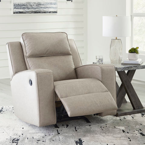 A light beige upholstered recliner chair with the footrest extended, shown in a bright living room setting next to a marble-top side table with a lamp.