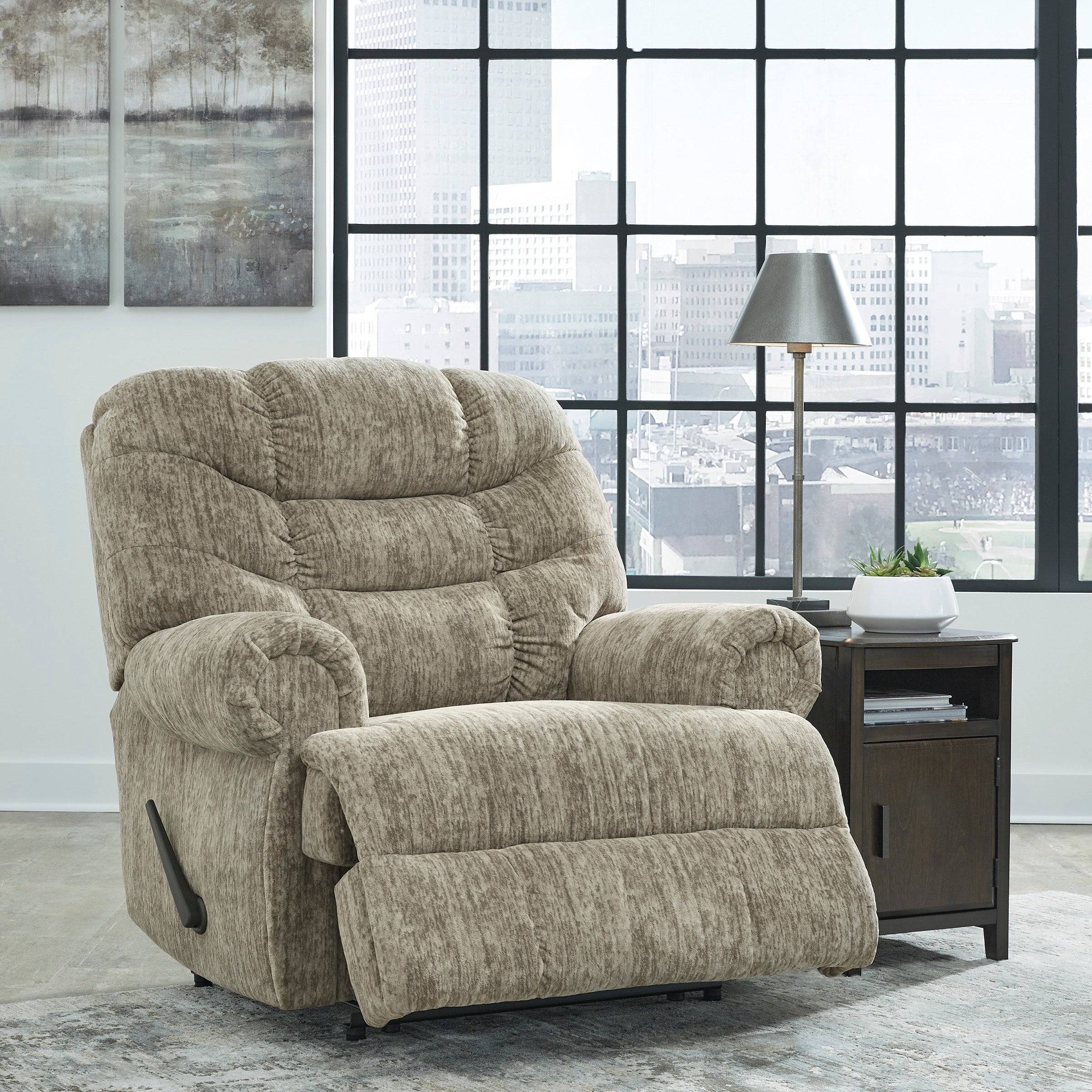 Beige recliner chair in a modern living room with large windows.