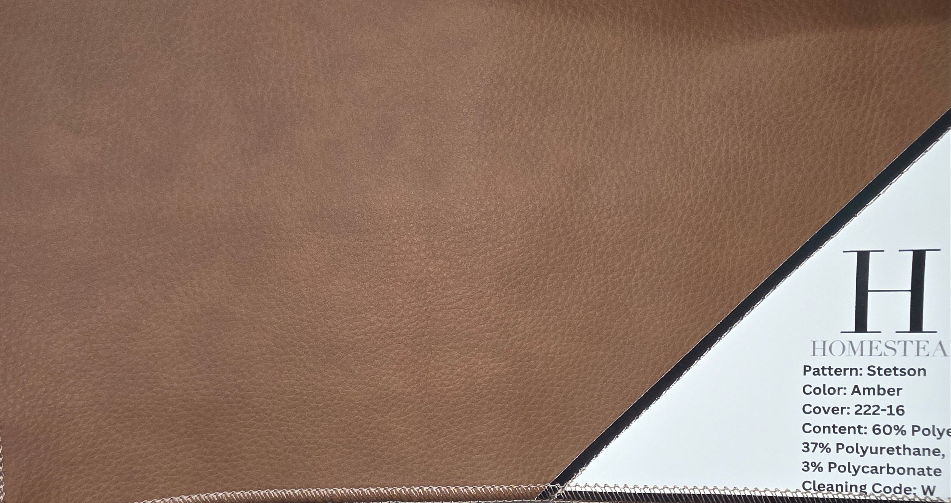 Close-up of a tan leather or faux-leather material swatch with visible stitching, alongside printed material samples labeled Homestead and color information for amber and pebble textures.