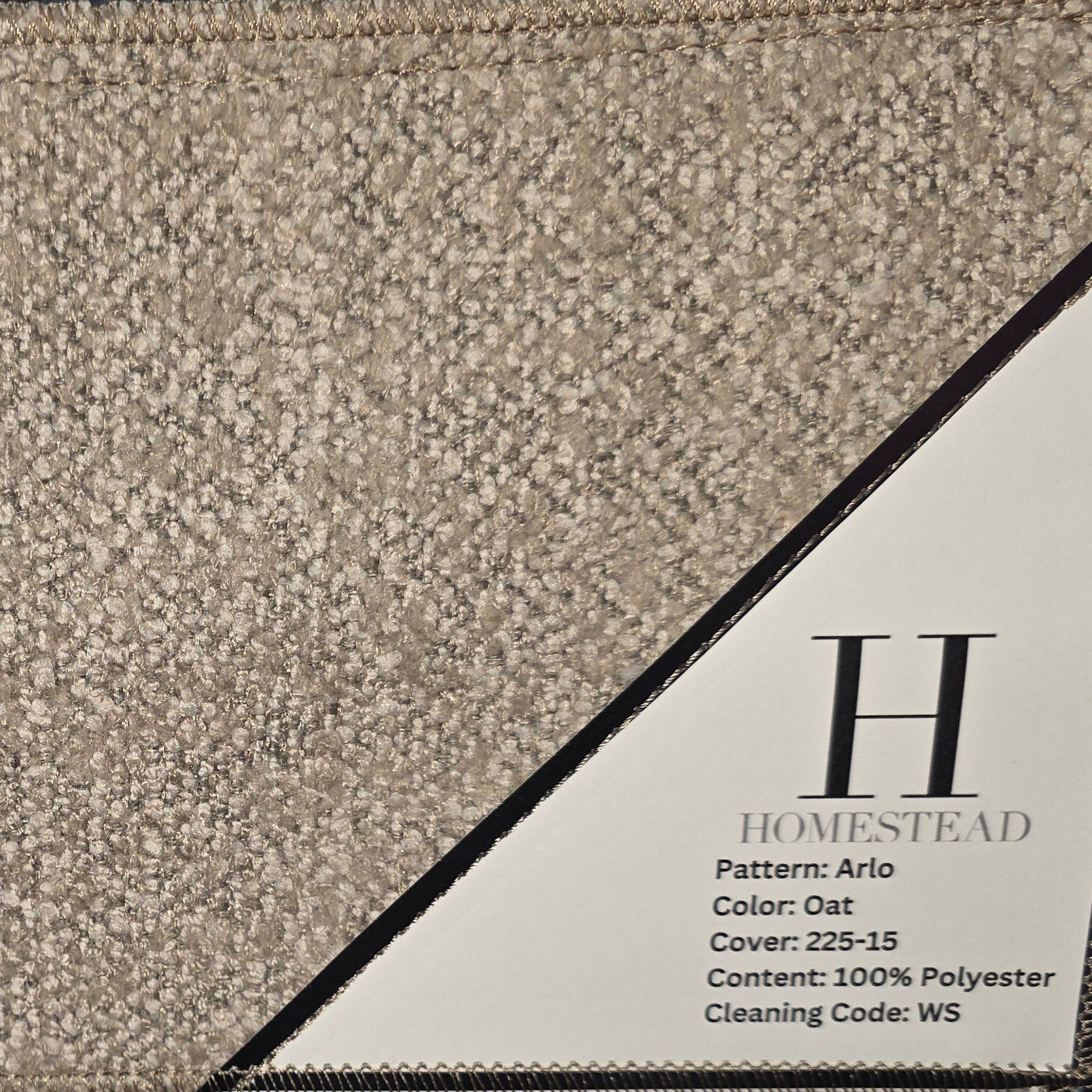 Two Homestead carpet samples stacked vertically on a display rack. The top sample is a textured beige patterned carpet with a white label, and the bottom sample is a dark charcoal gray patterned carpet with a matching label.