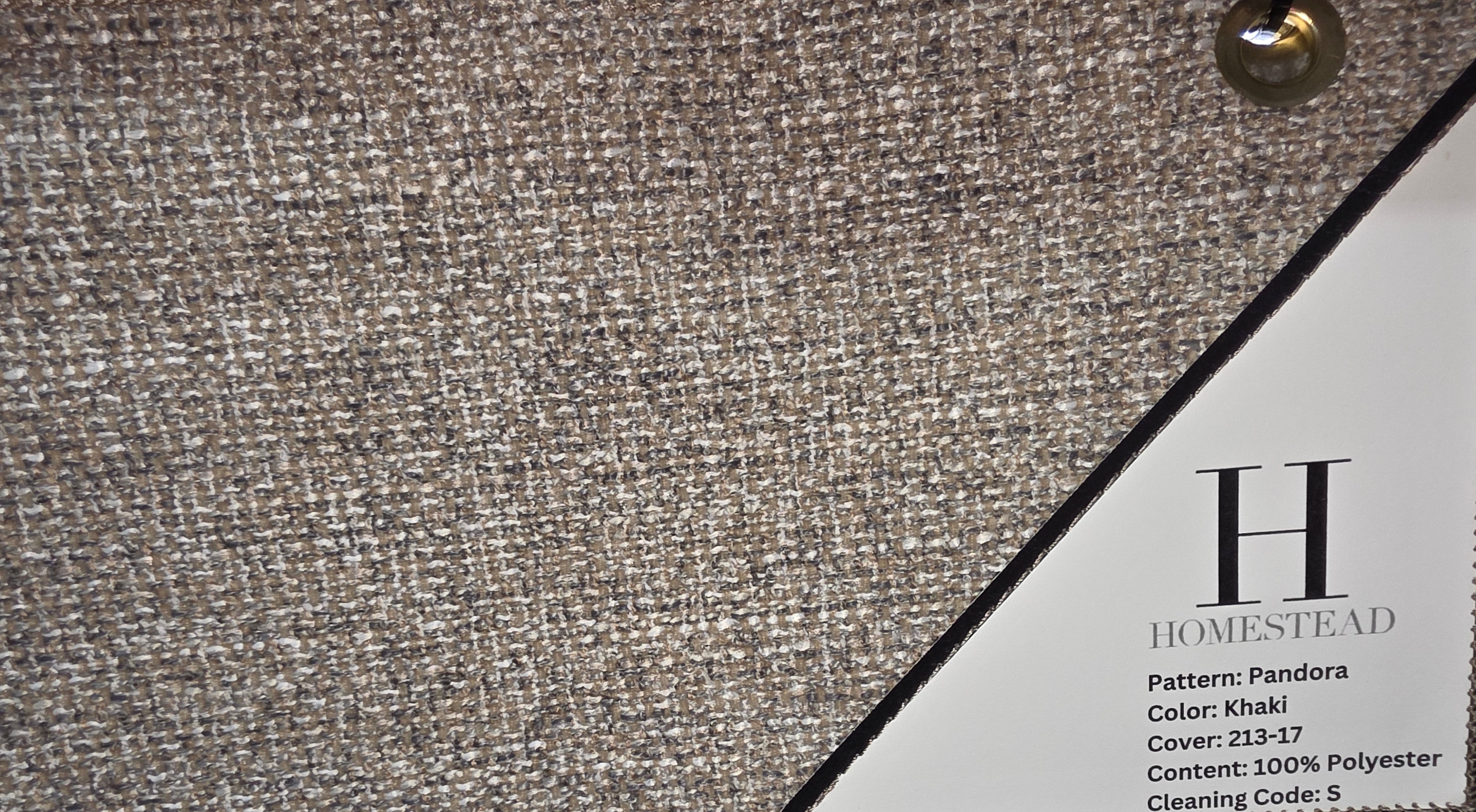Close-up of a fabric swatch labeled H Homestead Pattern: Pandora, showing a woven khaki-beige textile surface with two triangular sample tabs and printed material details.