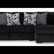 Black sectional sofa with patterned cushions on a white background