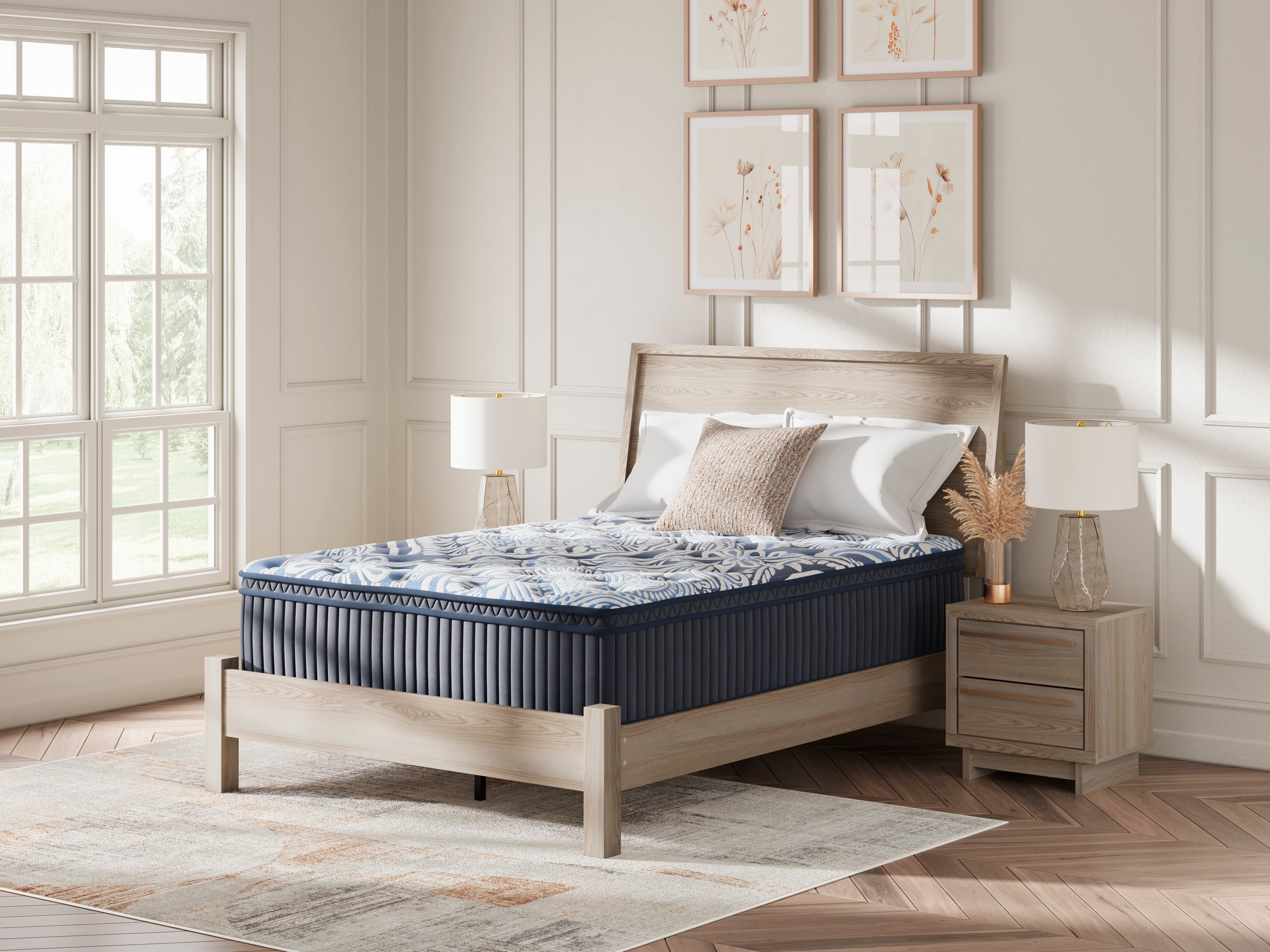 A plush queen mattress set in a bedroom setting, showing the mattress with a patterned cover, arranged pillows, and a wooden bed frame.