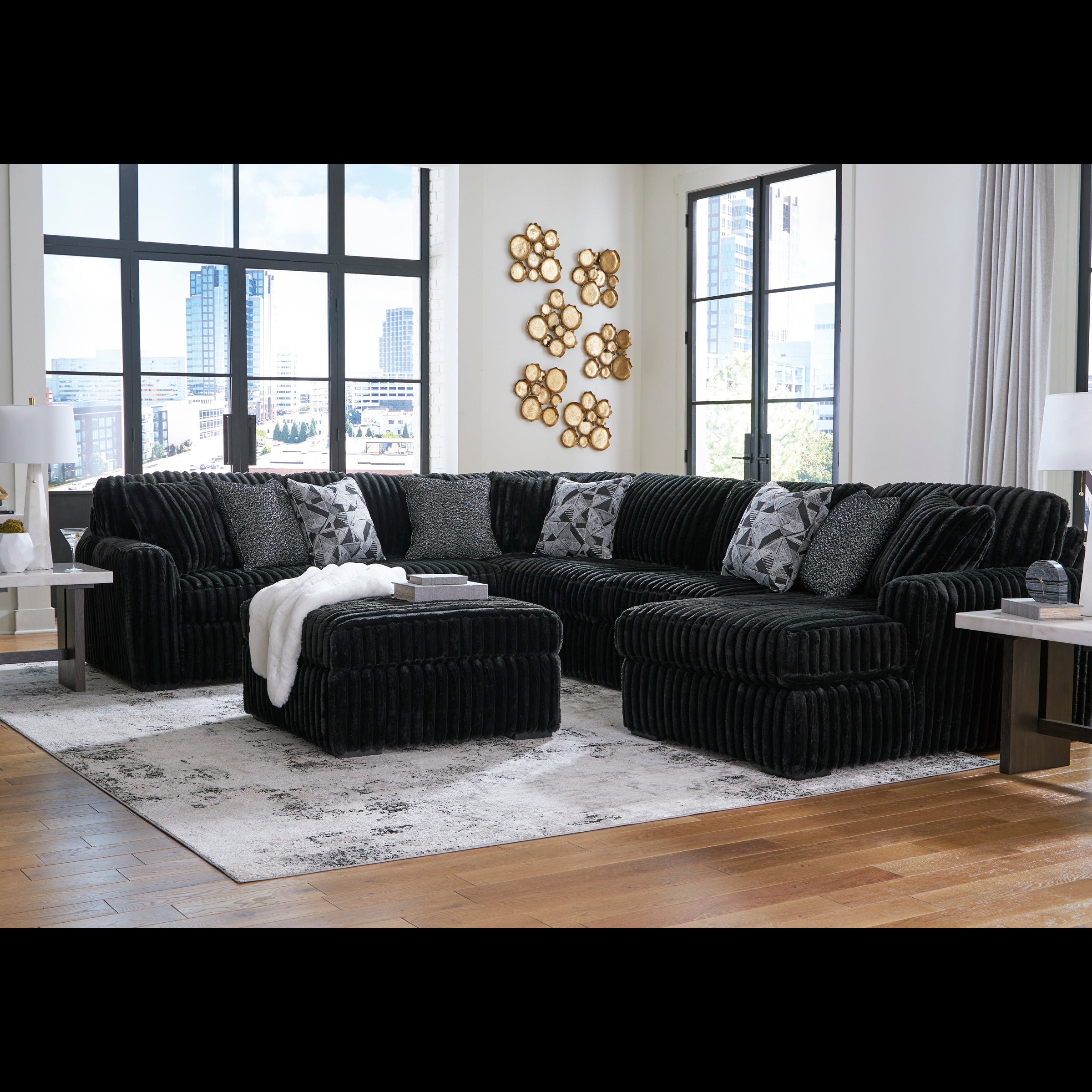 Black sectional sofa in a living room with large windows and decorative elements.